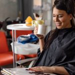 Smiling woman at hairdresser&rsquo;s looking at hair color palette.
