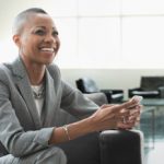Black businesswoman using cell phone on sofa in office